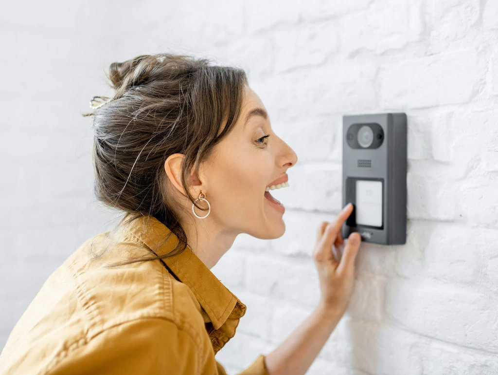 woman pressing a button on an apartment intercom system